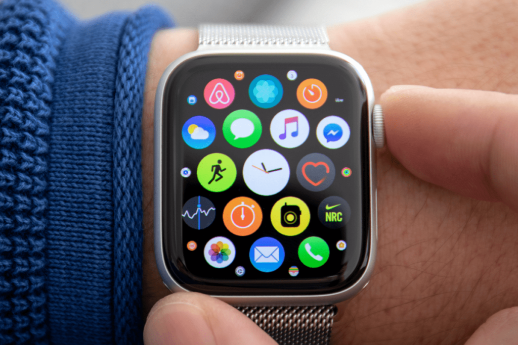 Two fingers pressing the Apple watch home button showing the home screen.
