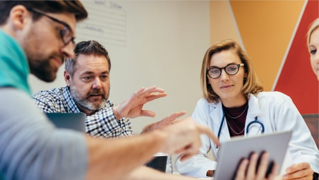 Doctors collaborating sitting at a table looking at tablet