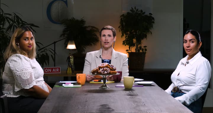 Three women seated around a conference table in a studio setting for a D2Bites episode
